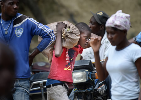 ドミニカ共和国とハイチとの国境で開かれていたマーケットで働く少年。何度も何度も荷物を持って両国を往復していた＝ハイチ・ベラデールで６月
