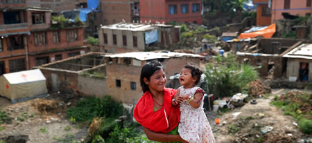 倒壊した家屋に住み続けているというサッテ・バンナラさん。長女トリスナちゃんを抱きながら「毎日が不安。子どものためにも早く普通の生活が送りたい」と語った＝バクタプルで