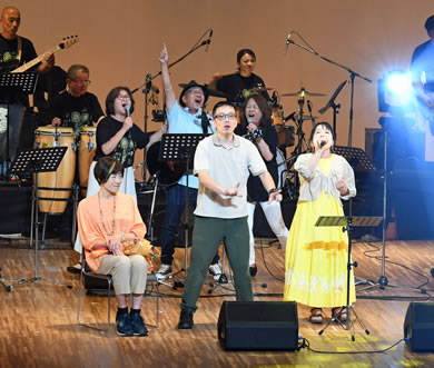 「わたぼうし大賞」を受賞し再歌唱するボーカルの原田奈生さん（前列右）、サインボーカルの久保田洋輔さん（前列中央）、作詩者の大矢治美さん（前列左）、作曲した山本享明さん（後列中央）