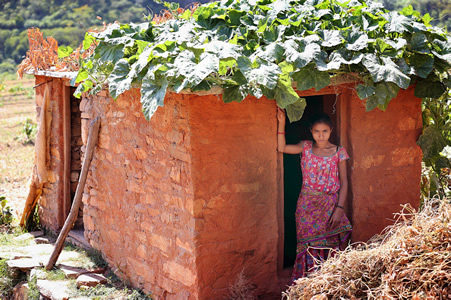 泥壁の生理小屋の前に立つギャヌ・マジさん＝ネパール・サラダ村で