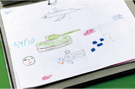 戦車と倒れた人などが描かれた絵。ワークショップでは人生で一番うれしかったことと悲しかったことをテーマに絵で表現し、発表する＝ヨルダン・ザルカで２０１６年、久保玲撮影