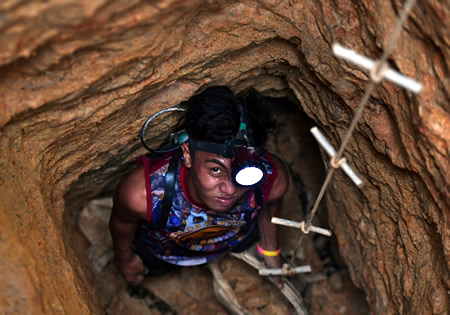 深さ６メートルの穴に入って掘った金鉱石を上からつり上げてもらうクリストファー・ジュド・エドリアさん＝フィリピン・カマリネスノルテ州パラカリエで

