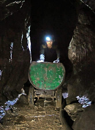 真っ暗なトンネルの中で、金鉱石をトロッコに載せて運ぶシェルドン・ダオ・アイさん＝フィリピン・ベンゲット州イトゴンで、川平愛撮影