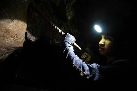 真っ暗なトンネルの中で岩を掘るシェルドン・ダオ・アイさん＝フィリピン・ベンゲット州イトゴンで