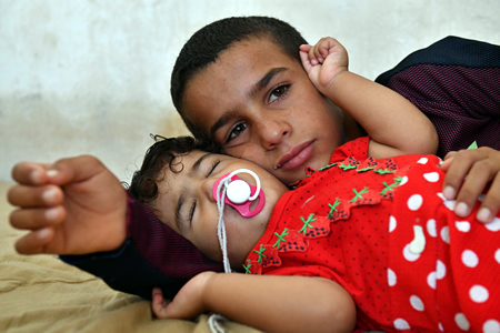 モスルの爆撃で両親を亡くしたジャサム君（上）とハジャルちゃん。ジャサム君は両親に代わり妹の面倒を見ている＝イラク・アルビル県のデバガ１キャンプで