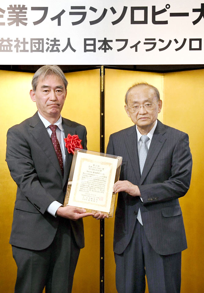 企業フィランソロピー賞を受賞し、表彰状を手にする毎日新聞社の砂間裕之・取締役常務執行役員(左）と浅野史郎・日本フィランソロピー協会会長