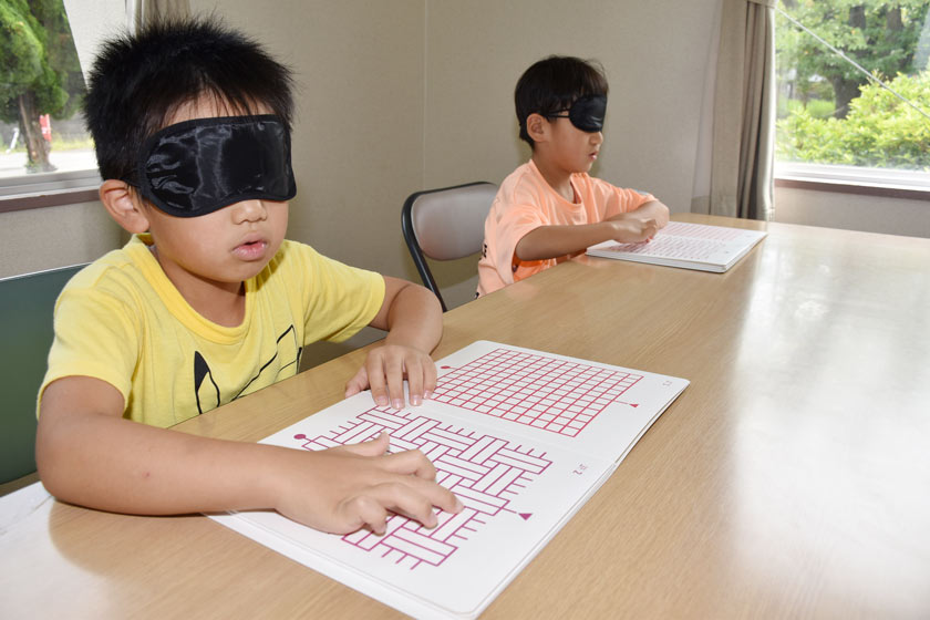 点字の線をたどって迷路をたどる子どもたち